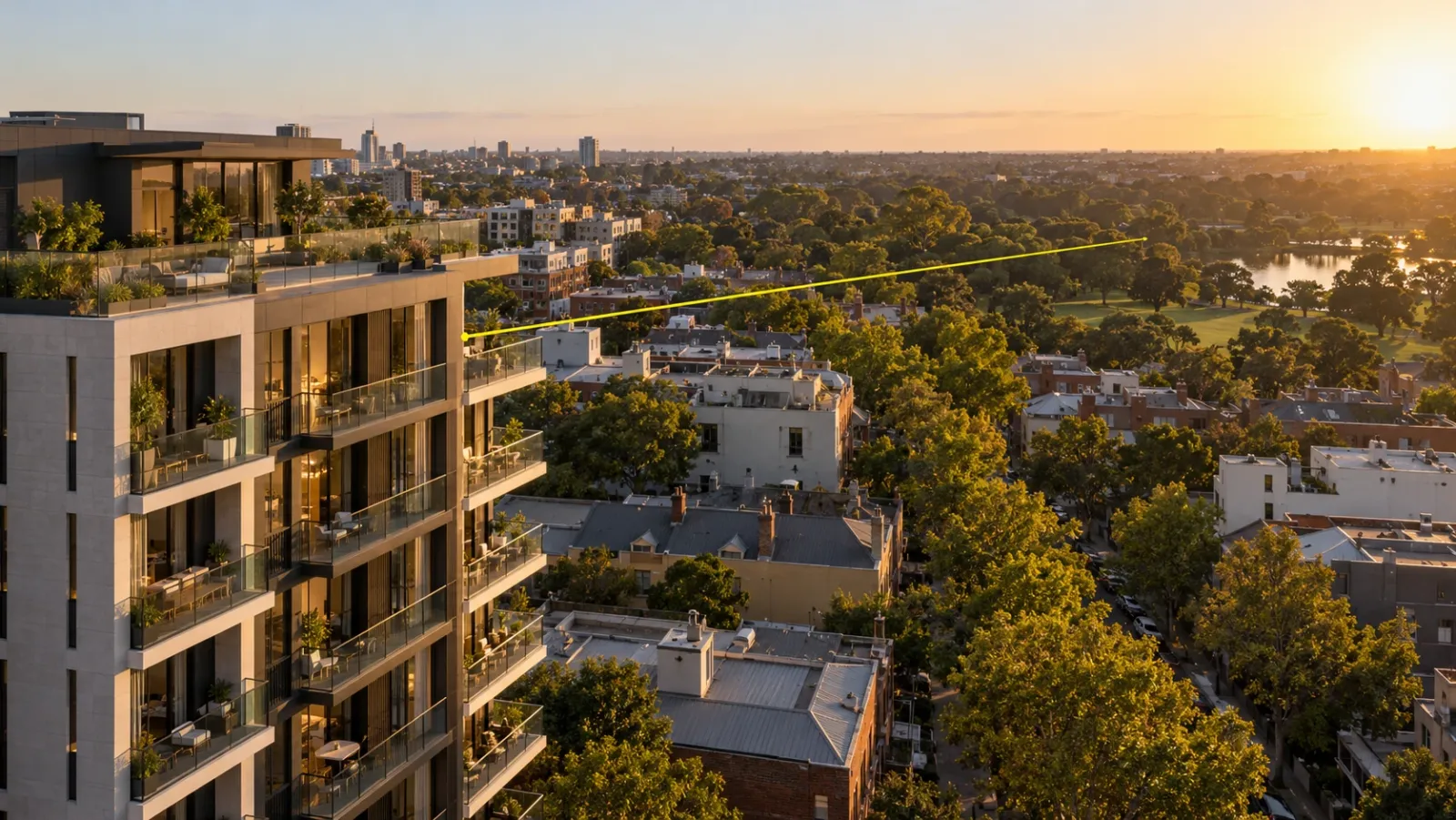 Low aerial view at golden hour of a new mid-rise apartment building with a rooftop terrace, city rooftops and a park beyond, and a thin yellow line running out from an upper balcony to show the view from that floor
