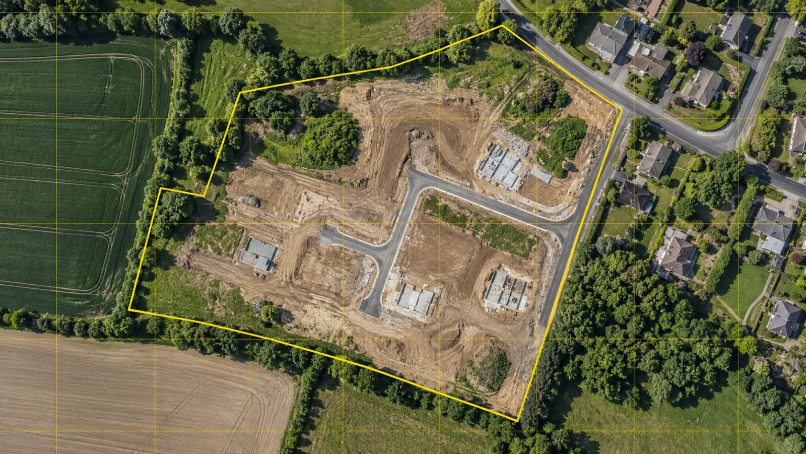 Top-down drone map of a development parcel at midday with a yellow grid of stitched map tiles and the parcel boundary outlined